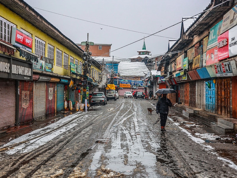 People walk with umbrellas to shield themselves against the snowfall in Sopore, Jammu and Kashmir, on December 12, 2024. Kashmir received the season"s first snowfall while a cold wave has gripped parts of north India with New Delhi waking up to 4.5 degrees Celsius this morning.