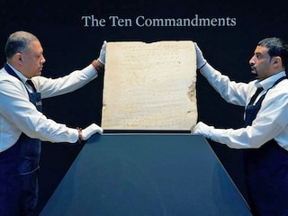Sotheby’s workers hold one of the most widely known and influential texts in history: the oldest inscribed stone tablet of the Ten Commandments during a press preview at Sotheby’s in New York, on December 9, 2024. 
Image: Timothy A. Clary / AFPÂ©
