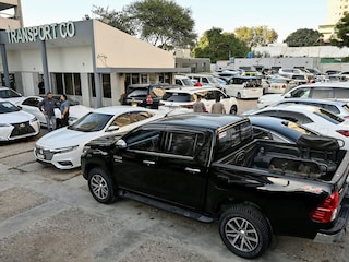 This photograph taken on November 11, 2024 shows car dealer Fahad Nazir (2L) speaking to a customer near a Toyota Hilux pick-up truck (front) locally known as "Dala", parked at his showroom yard in Karachi. Photography Asif HASSAN / AFP©