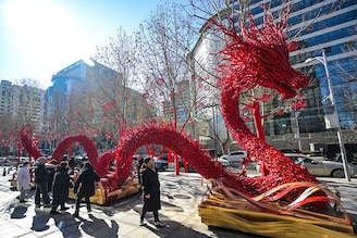 People stand around of a dragon figure made from dry branches on a street in Beijing on February 7, 2024, ahead of the Lunar New Year of the Dragon which falls on February 10.
