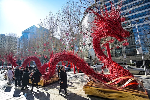People stand around of a dragon figure made from dry branches on a street in Beijing on February 7, 2024, ahead of the Lunar New Year of the Dragon which falls on February 10.