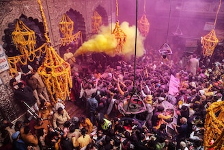 A priest (L) throws coloured powder over Hindu devotees during "Basant Panchami" festival celebrations, which mark the preparations for the arrival of spring, inside the Sri Bankey Bihari temple in Vrindavan on February 14, 2024.