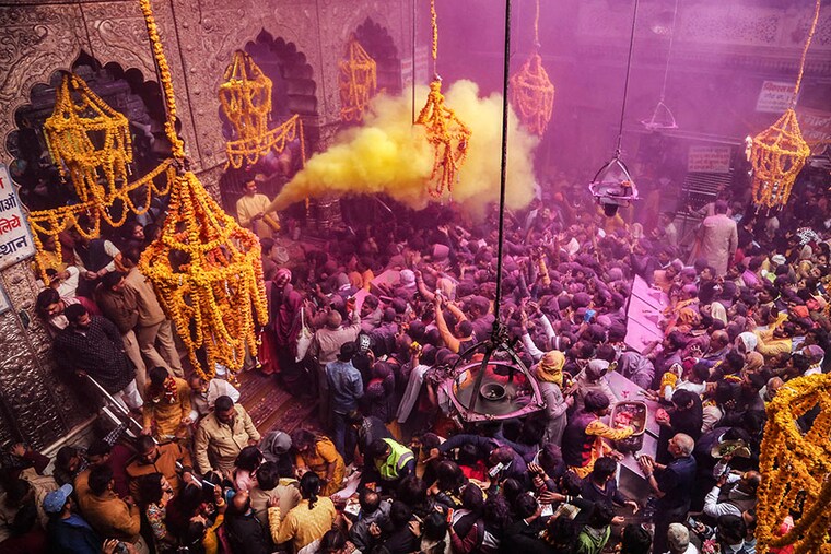 A priest (L) throws coloured powder over Hindu devotees during "Basant Panchami" festival celebrations, which mark the preparations for the arrival of spring, inside the Sri Bankey Bihari temple in Vrindavan on February 14, 2024.