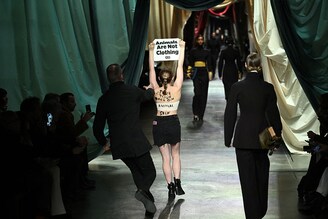 A security guard runs to stop a woman holding a poster reading "animals are not clothing" during the Fendi collection show at the Milan Fashion Week Womenswear Autumn/Winter 2024-2025 on February 21, 2024, in Milan.