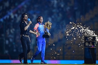 Mumbai Indians" captain Harmanpreet Kaur (R) carrying WPL trophy and Bollywood actor Shah Rukh Khan arrive during the opening ceremony of Women"s Premier League 2024 before the start of first T20 cricket match between Mumbai Indians and Delhi Capitals at the M. Chinnaswamy Stadium in Bengaluru on February 23, 2024.