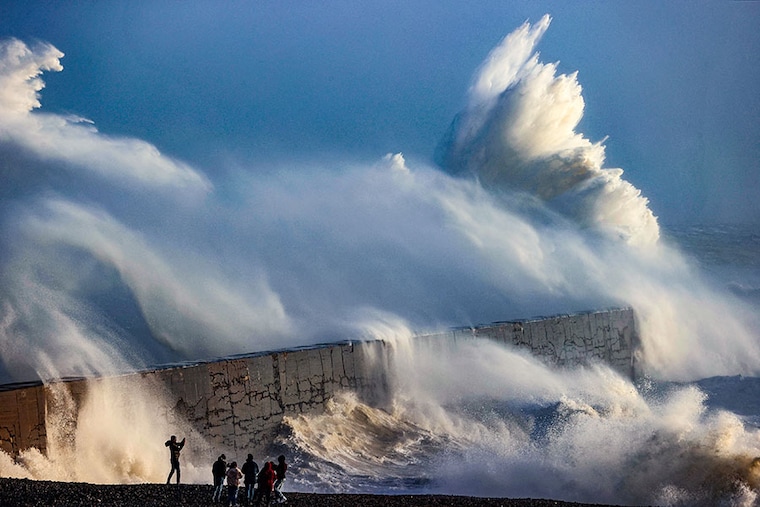 A person takes a photograph as waves break against the breakwater in Newhaven, England, on January 2, 2024, as Storm Henk brought strong winds and heavy rain across much of southern England.