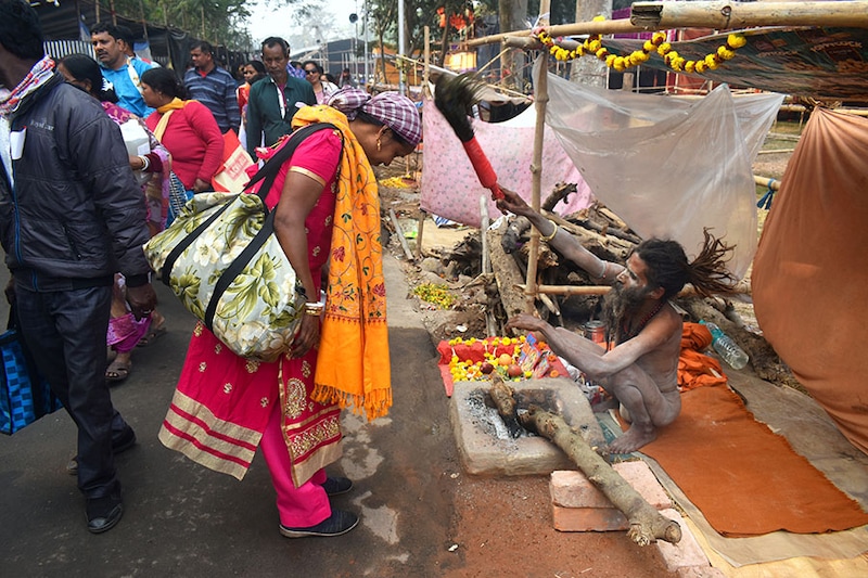 A Sadhu, or Hindu holy man, is giving blessings to a lady at a makeshift shelter before heading to Sagar Island for the one-day festival of ""Makar Sankranti"" in Kolkata, India, on January 7, 2024.