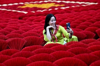 A tourist takes a selfie picture in front of incense sticks arranged in the form of a Vietnamese flag in a courtyard in the village of Quang Phu Cau on the outskirts of Hanoi. Image: Nhac Nguyen / AFP©