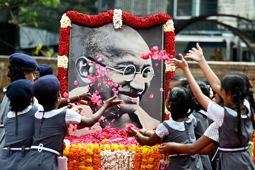 Indian school children throw rose flower petals over a portrait of Mahatma Gandhi to pay their tribute on the death anniversary of the Indian founding father in Chennai on January 30, 2024. The death anniversary of Gandhi, who is widely known in India as Bapu (father), is also observed as Martyrs" Day in the country.