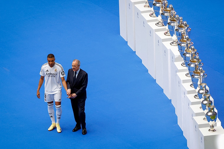 French forward Kylian Mbappe (L) poses with Real Madrid"s President Florentino Perez during his first appearance as a Real Madrid player at Santiago Bernabeu Stadium in Madrid on July 16, 2024, after signing his new five-season contract. Still celebrating Spain"s Euro 2024 triumph, Real Madrid fans have even more to cheer as French superstar Kylian Mbappe is officially presented to a packed-out Santiago Bernabeu stadium.
