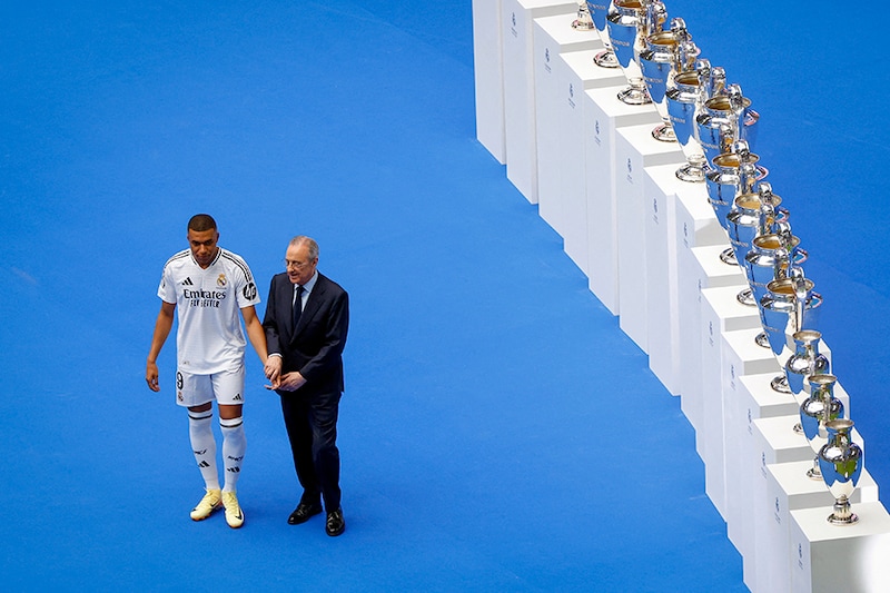 French forward Kylian Mbappe (L) poses with Real Madrid"s President Florentino Perez during his first appearance as a Real Madrid player at Santiago Bernabeu Stadium in Madrid on July 16, 2024, after signing his new five-season contract. Still celebrating Spain"s Euro 2024 triumph, Real Madrid fans have even more to cheer as French superstar Kylian Mbappe is officially presented to a packed-out Santiago Bernabeu stadium.