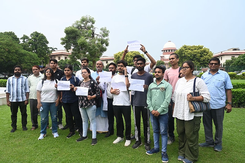 Students and others display placards in the precinct of the Supreme Court during a hearing on the NEET paper leak case on July 18, 2024, in New Delhi, India. The Supreme Court asked the National Testing Agency (NTA) to publish the city and centre-wise results of the NEET UG by noon on July 20, keeping the identity of the students masked. The next hearing will take place on Monday.