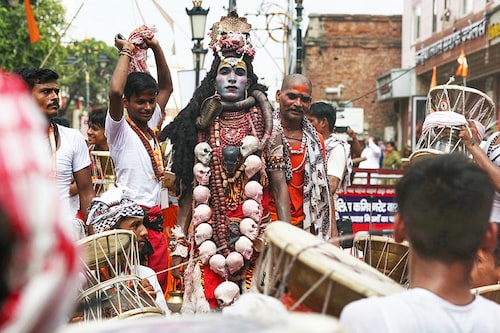 A Hindu devotee is dressed as Lord Shiva, and others play drums as they take part in a procession to celebrate a festival dedicated to Lord Shiva, which marks the first Monday of the monsoon (Sawan) month, in Varanasi on July 22, 2024.