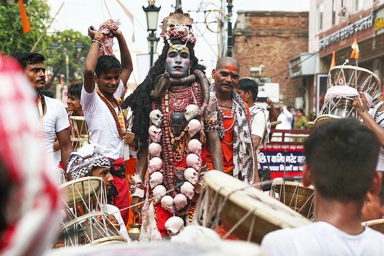 A Hindu devotee is dressed as Lord Shiva, and others play drums as they take part in a procession to celebrate a festival dedicated to Lord Shiva, which marks the first Monday of the monsoon (Sawan) month, in Varanasi on July 22, 2024.
