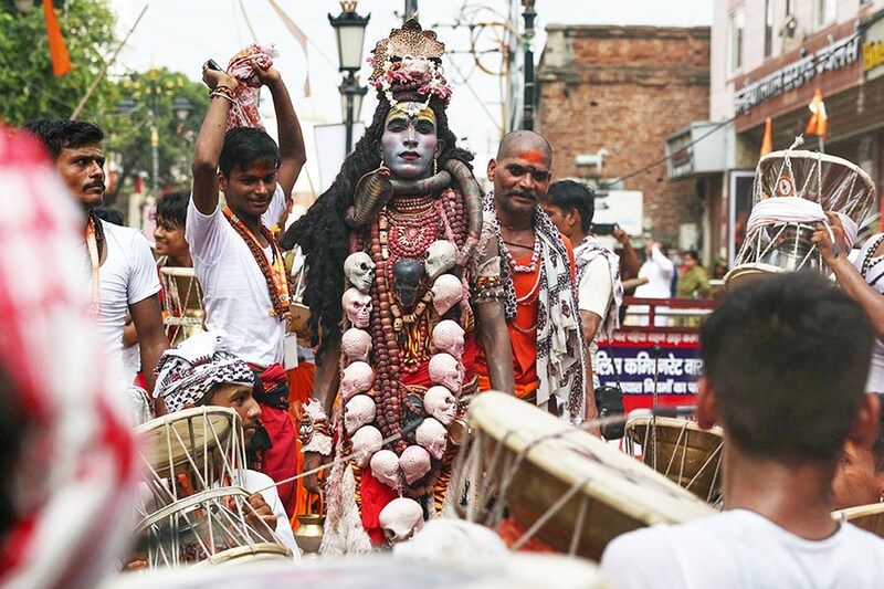 A Hindu devotee is dressed as Lord Shiva, and others play drums as they take part in a procession to celebrate a festival dedicated to Lord Shiva, which marks the first Monday of the monsoon (Sawan) month, in Varanasi on July 22, 2024.