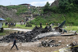 People stand at the site where a Saurya Airlines" plane crashed during takeoff at Tribhuvan International Airport in Kathmandu on July 24, 2024. It was a passenger plane carrying 19 people. While the pilot has survived, some others have been reported dead by the local police.