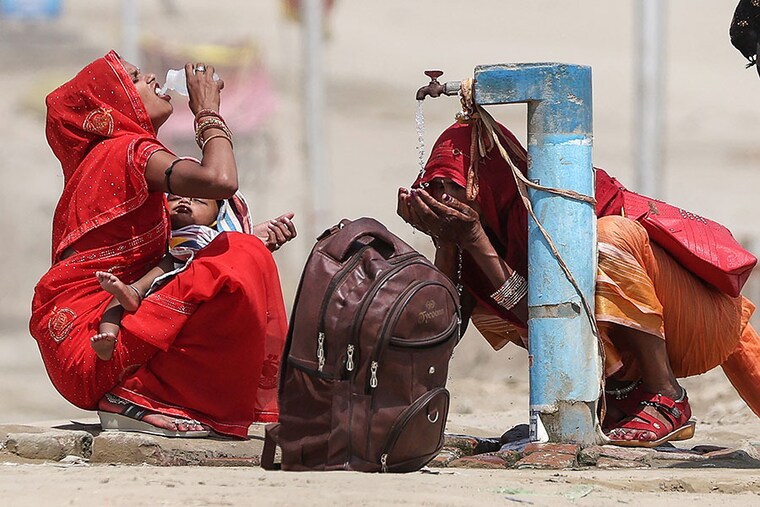 Women quench their thirst with tap water on a hot summer afternoon in Prayagraj that is gripped by a heatwave, on June 10, 2024. India"s heatwave is the longest ever to hit the country, the government"s top weather expert said on June 10 and also warned that people will face increasingly oppressive temperatures.