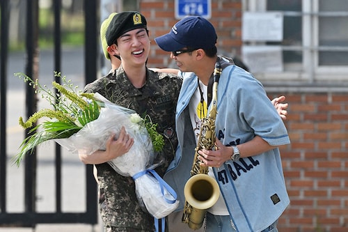K-pop boy band BTS member Jin (L) is greeted by fellow BTS member RM (R) after being discharged from his mandatory military service outside a military base in Yeoncheon. Image: Photography Jung Yeon-je / AFP