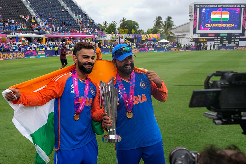 India"s Virat Kohli (left) and captain Rohit Sharma pose with the winners trophy after defeating South Africa in the ICC Men"s T20 World Cup final cricket match at Kensington Oval in Bridgetown, Barbados on Saturday, June 29, 2024.