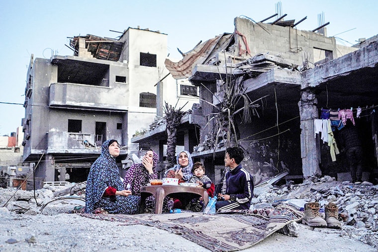 The Palestinian Al-Naji family eats an iftar meal, the breaking of fast, amidst the ruins of their family house on the first day of the Muslim holy fasting month of Ramadan, in Deir el-Balah in the central Gaza Strip on March 11, 2024, amid ongoing battles between Israel and the militant group Hamas.
