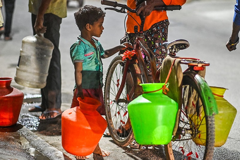 A boy holds a pot to fill water amid an ongoing water crisis in Bengaluru on March 14, 2024.