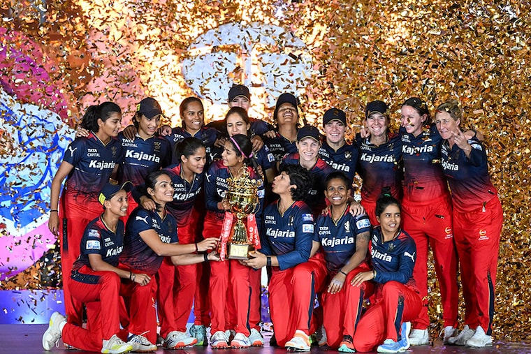 Royal Challengers Bangalore"s players hold the trophy after winning the final match of the Women"s Premier League (WPL) Twenty20 cricket against the Delhi Capitals at the Arun Jaitley Stadium in New Delhi, on March 17, 2024.