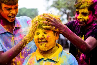 A boy is reacting while getting smeared with colors during the celebrations of the spring festival of "Holi" at a school in Kolkata, India, on March 22, 2024.