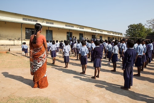 Karon, India - March 07, 2013: Several school boys and girls are standing in line while a female teacher in a orange sari is watching them. (Photo by Christian Ender/Getty Images) Karon, India - March 07, 2013: Several school boys and girls are standing in line while a female teacher in a orange sari is watching them. (Photo by Christian Ender/Getty Images)