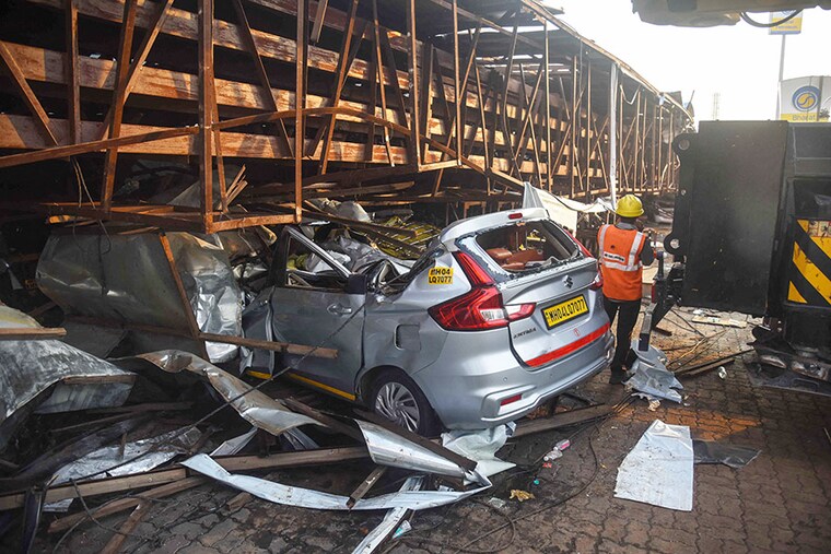 A rescue team member is seen alongside a vehicle crushed under a giant billboard that collapsed onto a petrol station during a rain storm in the city"s eastern suburb of Ghatkopar, Mumbai, on May 13, 2024. At least fourteen people were killed and dozens more injured, even as emergency services say a few people are still trapped under it, and a rescue operation is underway.