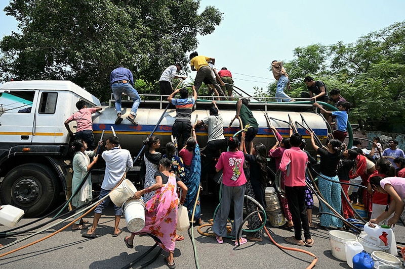 Residents place pipes inside a municipal tanker to collect water at a low-income neighbourhood in New Delhi on May 15, 2024.