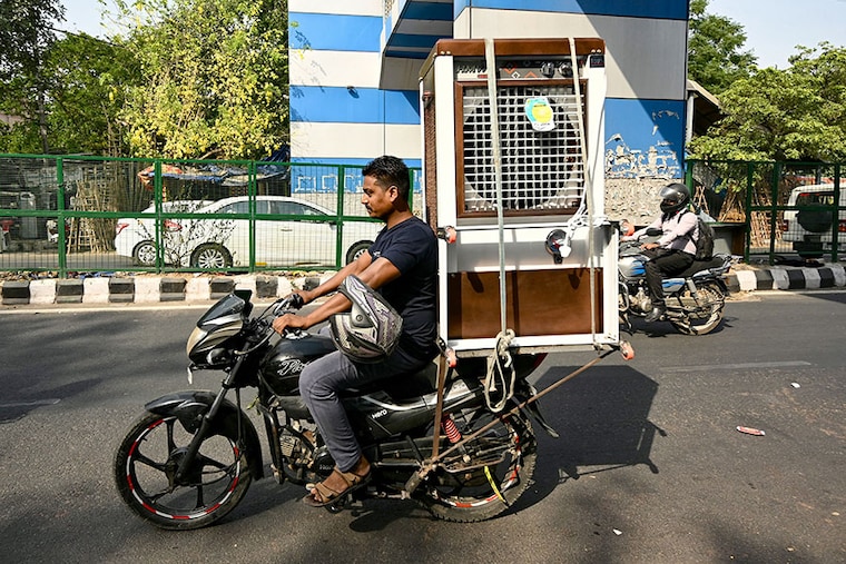 A man drives home a newly purchased air cooler on a hot summer afternoon in New Delhi on May 20, 2024, amid the ongoing heatwave. The IMD issued a red alert for extreme heat in Delhi, warning of heat-related illnesses like heat stroke as temperatures soared past 47°C in parts of the National Capital Region (NCR) and parts of neighbouring states.