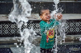 A boy seen cooling off with fountain water on a scorching summer day. Kashmir valley experienced a significant rise in temperatures with several areas recording the highest temperatures in decades. The Meteorological Department predicted the continuation of the heatwave in the next month too. (Photo by Saqib Majeed/SOPA Images/LightRocket via Getty Images)