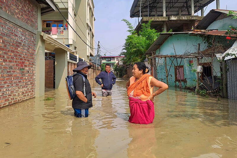 People wade through a flooded street on May 29, 2024, after heavy rains lashed Imphal, Manipur, due to cyclone Remal"s landfall. A powerful cyclone that smashed into low-lying Bangladesh and India killed at least 65 people, including in torrential rain storms in its wake, state government officials and media said on May 29.