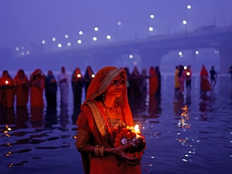 Devotees worship the Sun god as they stand in the polluted waters of the river Yamuna on a smoggy morning in New Delhi, India, on November 8, 2024, during the Hindu religious festival of Chhath Puja.