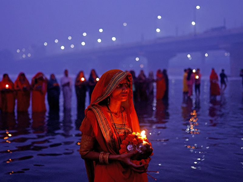 Devotees worship the Sun god as they stand in the polluted waters of the river Yamuna on a smoggy morning in New Delhi, India, on November 8, 2024, during the Hindu religious festival of Chhath Puja.