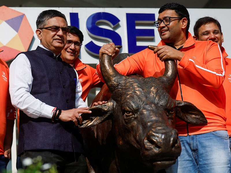 Swiggy"s MD and Group CEO, Sriharsha Majety, and the National Stock Exchange of India"s MD and CEO, Ashishkumar Chauhan, pose with the statue of the NSE bull ahead of the listing ceremony of its Initial Public Offering (IPO) at the NSE in Mumbai, India, on November 13, 2024.