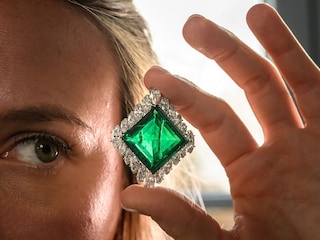 A Christie"s employee poses with The Aga Khan Emerald, a Cartier emerald and diamond brooch made with a square-shaped emerald of 37.00 carats. 
Image: Fabrice Coffrini / AFP