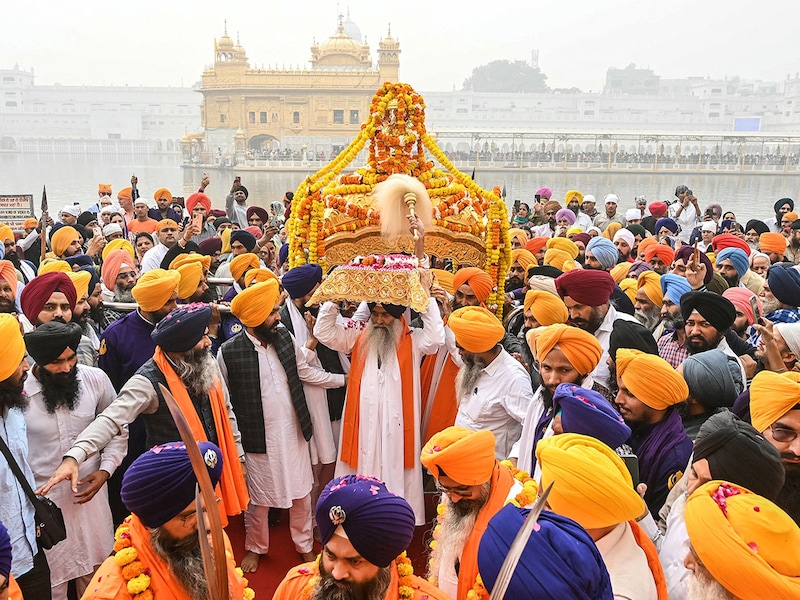 A Sikh priest (C) carries the Guru Granth Sahib during a religious procession at the Golden Temple in Amritsar on November 14, 2024, on the eve of Guru Nanak Dev"s birth anniversary.