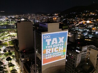 A group of environmental activists projects on a building slide that reads, "Tax the super-rich for the people and planet", on November 18, 2024, in Rio de Janeiro, Brazil, during the G20 Summit. ONG environment demonstrates projecting slides to demand governments to take actions and tax the superriches for the benefit of the planet.