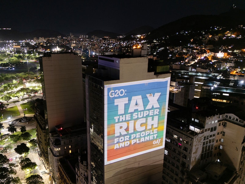 A group of environmental activists projects on a building slide that reads, "Tax the super-rich for the people and planet", on November 18, 2024, in Rio de Janeiro, Brazil, during the G20 Summit. ONG environment demonstrates projecting slides to demand governments to take actions and tax the superriches for the benefit of the planet.