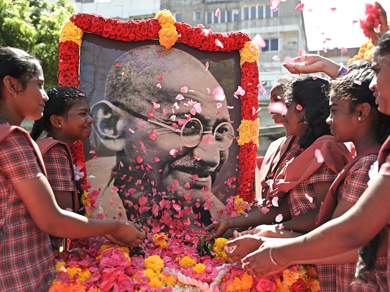 School children scatter rose petals before a portrait of Mahatma Gandhi on the occasion of Gandhi"s birth anniversary, in Chennai on October 2, 2024.