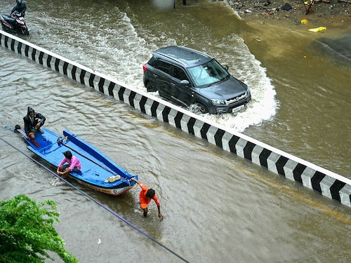 People wade through a flooded street amid heavy rainfall in Chennai on October 16, 2024.