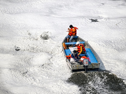Civic workers spray defoamer on the polluted waters of river Yamuna laden with foam, in New Delhi on October 22, 2024.