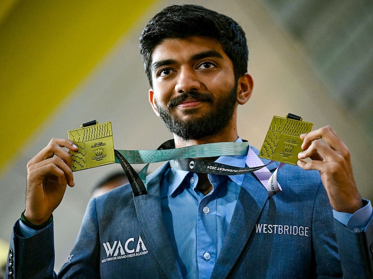 Gold medallist grandmaster Dommaraju Gukesh, shows his medals upon his arrival at the Chennai International Airport in Chennai on September 24, 2024, after his win at the 45th FIDE Chess Olympiad Budapest 2024.