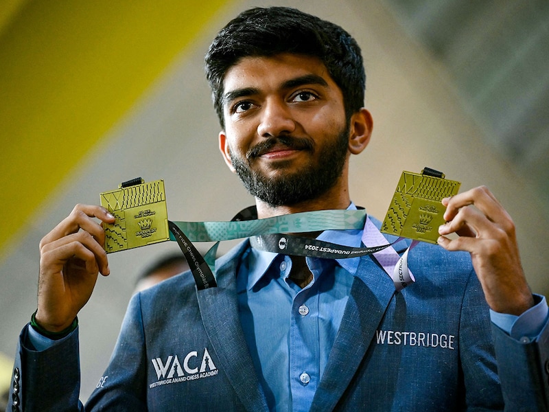 Gold medallist grandmaster Dommaraju Gukesh, shows his medals upon his arrival at the Chennai International Airport in Chennai on September 24, 2024, after his win at the 45th FIDE Chess Olympiad Budapest 2024.