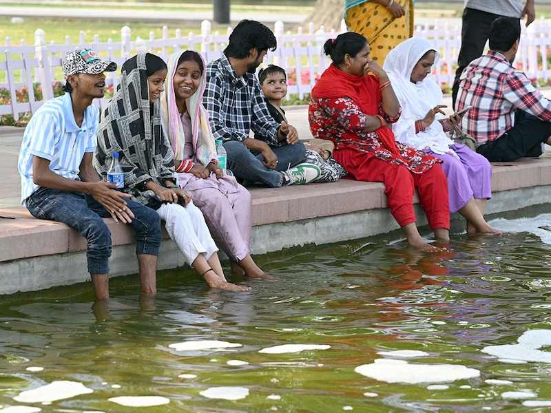 Visitors cool their feet in water to beat the heat at the India Gate lawn on a hot summer afternoon on April 9, 2025, in New Delhi, India. The India Meteorological Department (IMD) issued a heatwave warning in Delhi-NCR for the next two days.