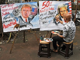 A teacher from the Gurukul School of Art paints a poster of US President Donald Trump, announcing a double tariff on Indian goods from 25 percent to 50 percent outside his art school on August 7, 2025, in Mumbai. A double tariff will impact key sectors like auto parts, jewellery, textiles, chemicals, seafood, machinery, mechanical appliances, gems, and leather. The 25 percent duty announced on July 31 has come into effect from August 7, and the additional 25 percent will be implemented by the US from August 27.