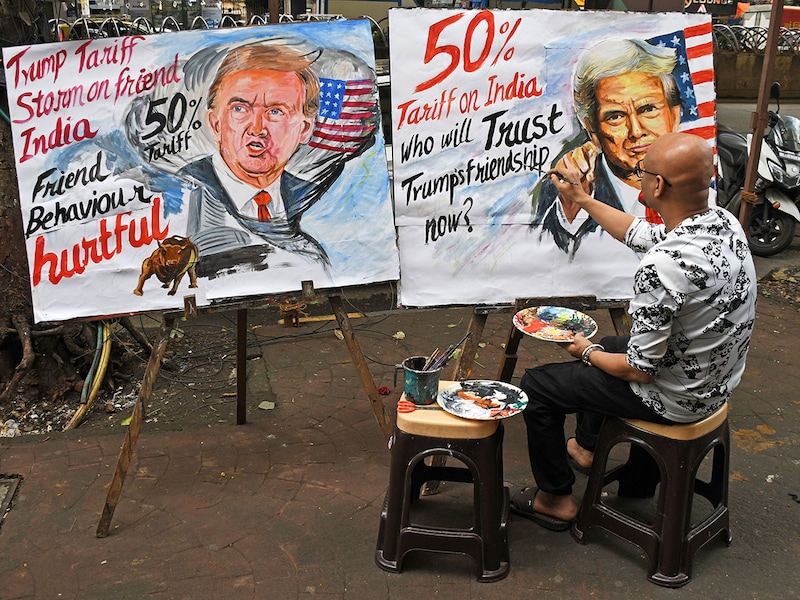 A teacher from the Gurukul School of Art paints a poster of US President Donald Trump, announcing a double tariff on Indian goods from 25 percent to 50 percent outside his art school on August 7, 2025, in Mumbai. A double tariff will impact key sectors like auto parts, jewellery, textiles, chemicals, seafood, machinery, mechanical appliances, gems, and leather. The 25 percent duty announced on July 31 has come into effect from August 7, and the additional 25 percent will be implemented by the US from August 27.