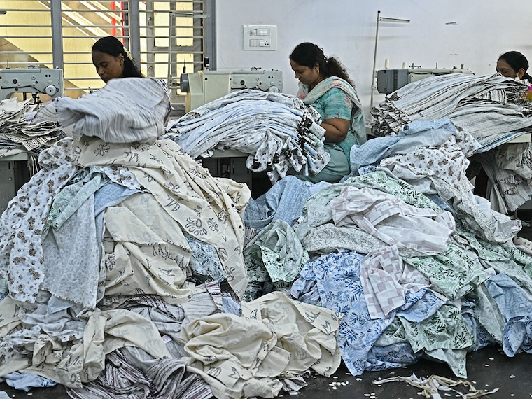 Garment workers tailor clothes on sewing machines at an apparel manufacturing unit in Bengaluru on August 25, 2025. US President Donald Trump has threatened to double import duties on India from 25 to 50 percent by August 27, to punish New Delhi for buying oil from Russia, saying the purchases help Moscow fund its invasion of Ukraine." Indian exporters are scrambling for options to mitigate the fallout as it threatens to upend low-margin, labour-intensive industries ranging from gems and jewellery to textiles and seafood.