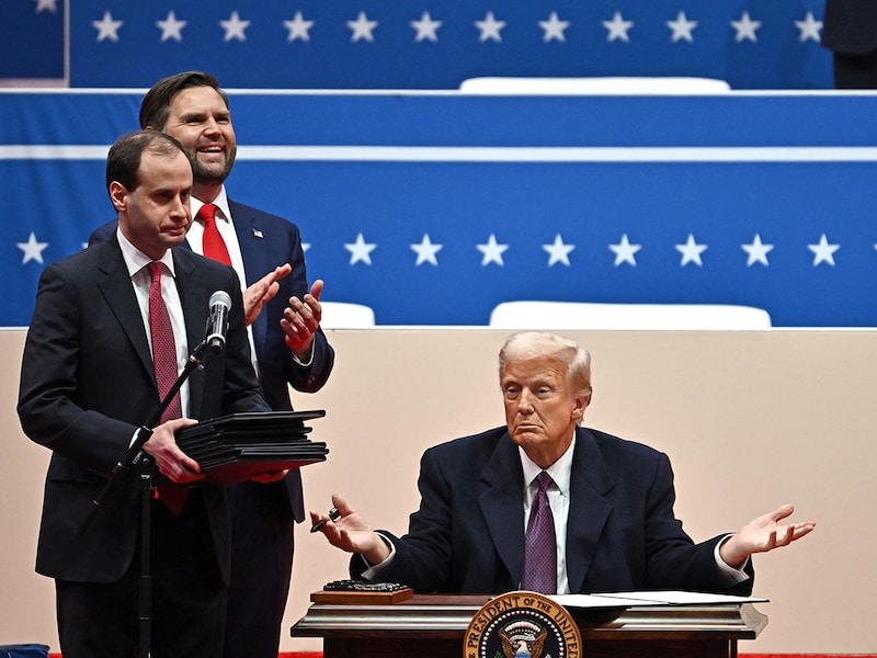 US President Donald Trump gestures as he signs executive orders during the inaugural parade inside Capital One Arena in Washington, DC, on January 20, 2025.
